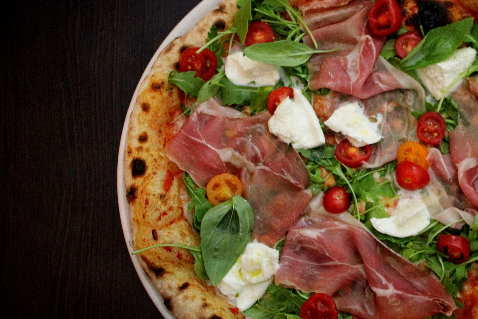 Frisch belegte Pizza mit Prosciutto, Rucola und Mozzarella