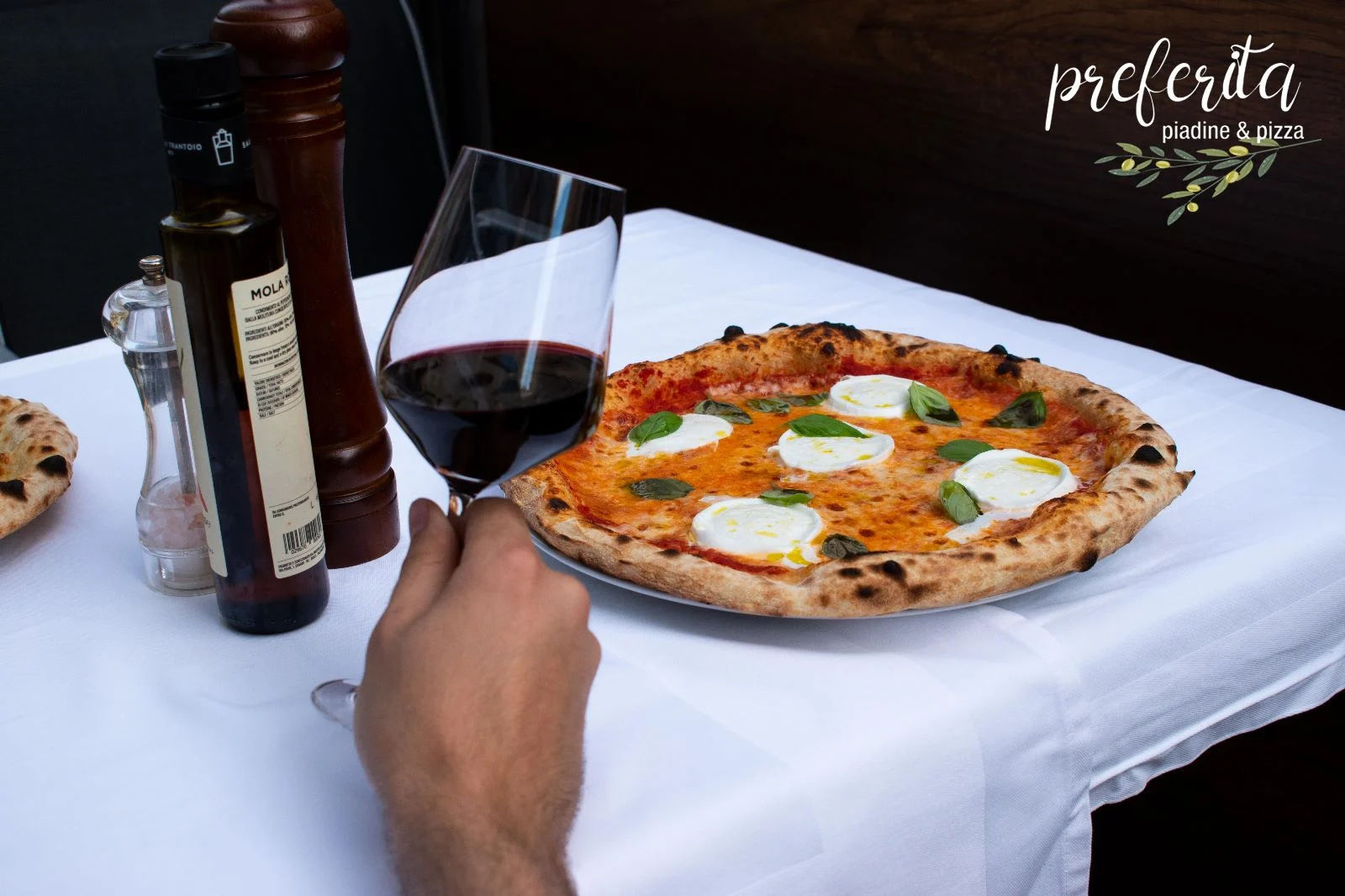 Pizza und ein Glas Rotwein am gedeckten Tisch